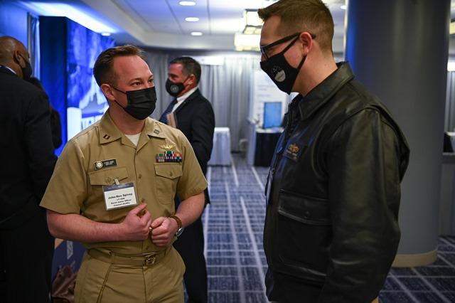 Naval Junior Officer Counsel (NJOC) Director Lt. John-Rex Spivey (left) discusses NJOC with an attendee at the 34th Surface Naval Association Symposium earlier this year. NJOC is a management advisory group designed to bridge the communications gap between junior and senior leaders. It recently launched a new online discussion tool — called the Acceleration Series — for sharing ideas, insights and concerns with senior leadership. (U.S. Navy photo by Michael Walls)