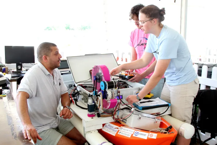 Competitors with Lake Superior State University’s Team AMORE (Autonomous Maritime Operations and Robotics Engineering) inspect their unmanned surface vehicle (USV) during the 16th annual RoboBoat competition in Sarasota, Florida. (Photo courtesy of RoboBoat)