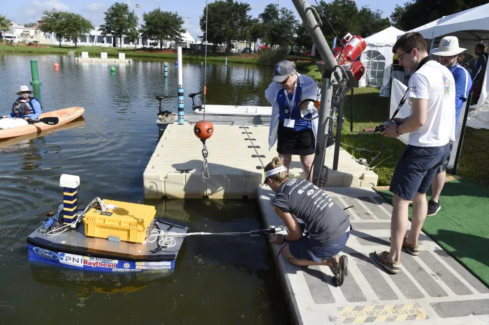 Kelly Cooper, center, a program manager in the Office of Naval Research's (ONR) sea warfare and weapons, ship systems and engineering research division, observes as a student designed autonomous robotic boat from the University of Michigan tests its thrusters prior to navigating through an aquatic obstacle course during the 2018 International RoboBoat Competition held at Reed Canal Park in South Daytona, Fla. (U.S. Navy photo by John F. Williams/Released)