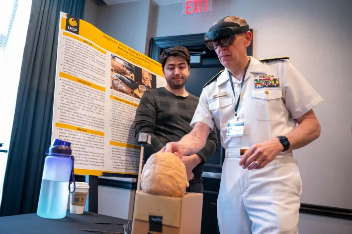 Chief of Naval Research Rear Adm. Lorin Selby learns about the scientific research conducted by a University of Central Florida student during the recent Specialized Inter-American Naval Conference on Science, Technology and Innovation (SIANC-ST&I) in Orlando, Florida. (U.S. Navy photo by Michael Walls)