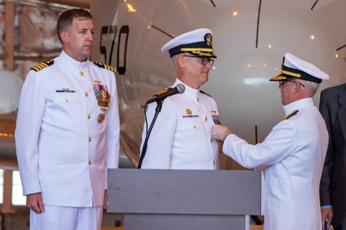 Chief of Naval Research (CNR) Rear Adm. Kurt Rothenhaus (right) pins a medal on outgoing Office of Naval Research Global Commanding Officer Capt. Matthew Farr (left), as former CNR Rear Adm. Lorin Selby (retired) looks on. During a June 13 change-of-command ceremony at Naval Air Station Patuxent River, Maryland, Farr was relieved by Capt. Andy “Big Tuna” Berner.