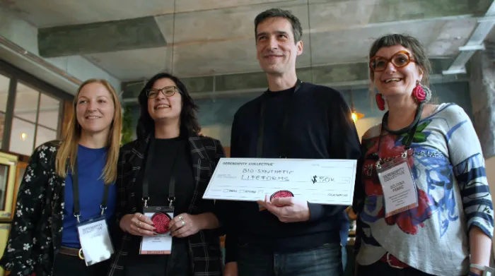 The team from Bio-Synthetic Lifeforms holds a mock check for $50,000 as one of the three winning grantees from the Serendipity Collective. (Photo courtesy of IdeatePlus)