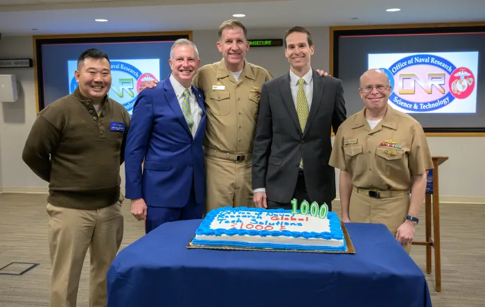 Rear Adm. Kurt Rothenhaus (right), celebrates the 1,000th request sent to TechSolutions — along with the director of TechSolutions, Jason Payne (center right); Capt. Andy Berner (center), commanding officer, ONR Global; John Coffey (center left), TechSolutions; and Command Master Chief Andrew Chupashko (left) — at ONR headquarters in Arlington, Virginia. (U.S. Navy photo by Michael Walls)