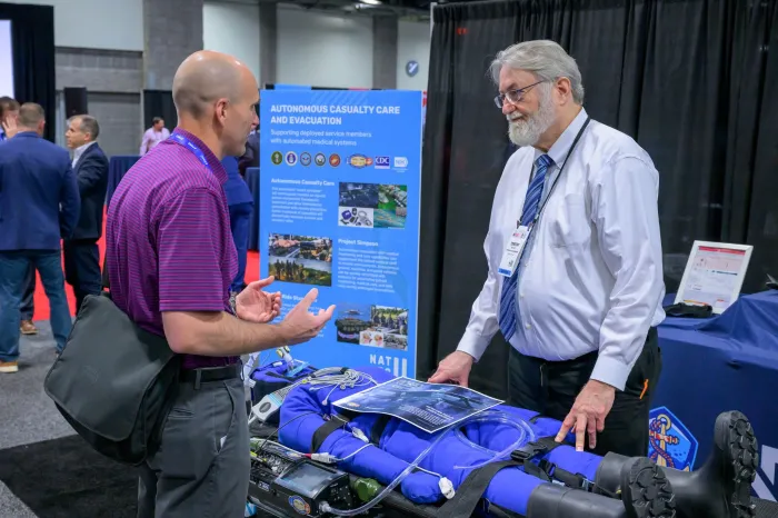 Dr. Timothy Bentley (right), a program officer in ONR’s Warfighter Performance Department, discusses the Autonomous Casualty Care and Evacuation system at Modern Day Marine in Washington, D.C. (U.S. Navy photo by Michael Walls)