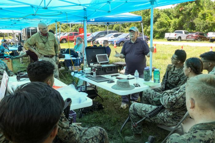 Peter DeSalva (standing, left), an ONR subject matter expert and support contractor, and Dr. John Tucker (standing, right), a Naval Research Laboratory physicist, teach Marines about the Portable Fluid Analyzer Plus system during the Technology Operational Experimentation Exercise 2022 at Camp Lejeune, North Carolina. (U.S. Marine Corps photo by Lance Cpl. Jessica J. Mazzamuto)