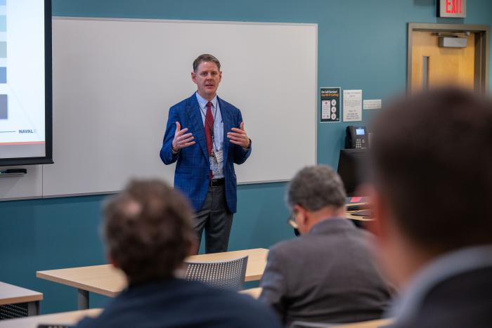 Scott Bewley, NavalX’s deputy director of business operations, addresses attendees at the 2024 Naval Science and Technology (S&T)/Combat Systems/Technology, Systems and Ships Symposium held Dec. 9-12 in Arlington, Virginia. (U.S. Navy photo by Michael Walls)