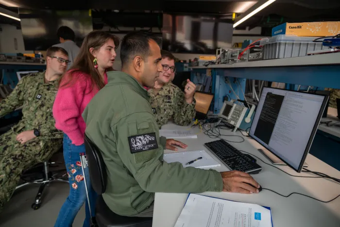 At the Naval Postgraduate School, Naval Research Enterprise Internship Program (NREIP) intern Calla Woodruff Lyons (center, standing) engaged in critical space systems research.