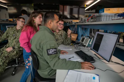 At the Naval Postgraduate School, Naval Research Enterprise Internship Program (NREIP) intern Calla Woodruff Lyons (center, standing) engaged in critical space systems research.