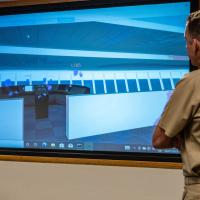 Capt. Andy Berner, ONR Global commanding officer, observes a screen view of the virtual bridge simulator during a test of the commercially available application.