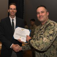 ason Payne (left), director, ONR Global TechSolutions, presents Lt. Cmdr. Sam Hughes (right), with the Gold Star, awarded by the Secretary of the Navy, while ONR Global Executive Officer Capt. Eric Hutter (not pictured), recites the commendation to the audience inside the base theater at Naval Air Station Patuxent River on Oct. 26, 2023. (Photo by Chief Petty Officer Patrick Gordon)