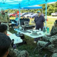 Peter DeSalva (standing, left), an ONR subject matter expert and support contractor, and Dr. John Tucker (standing, right), a Naval Research Laboratory physicist, teach Marines about the Portable Fluid Analyzer Plus system during the Technology Operational Experimentation Exercise 2022 at Camp Lejeune, North Carolina. (U.S. Marine Corps photo by Lance Cpl. Jessica J. Mazzamuto)